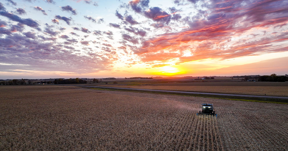 Combine harvesting a field at sunset
