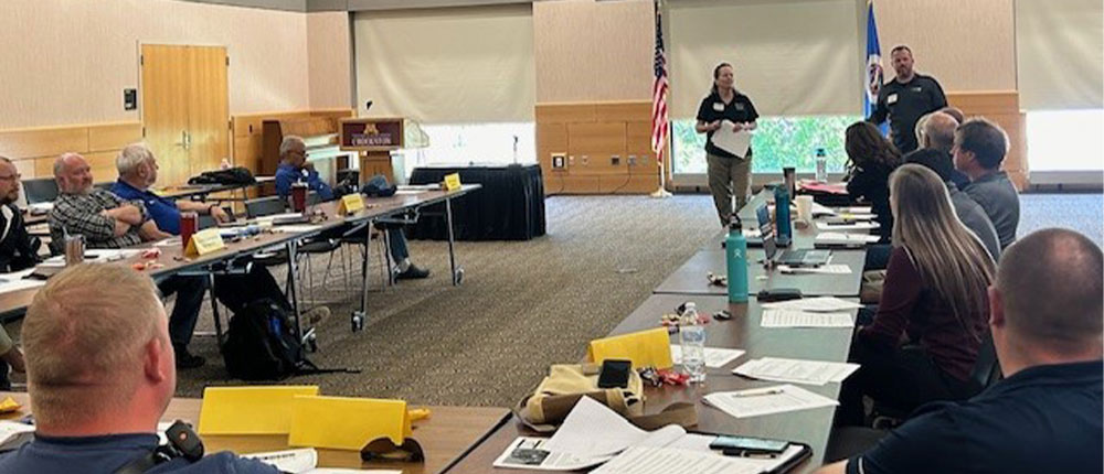 man and woman presenting in front of group of people