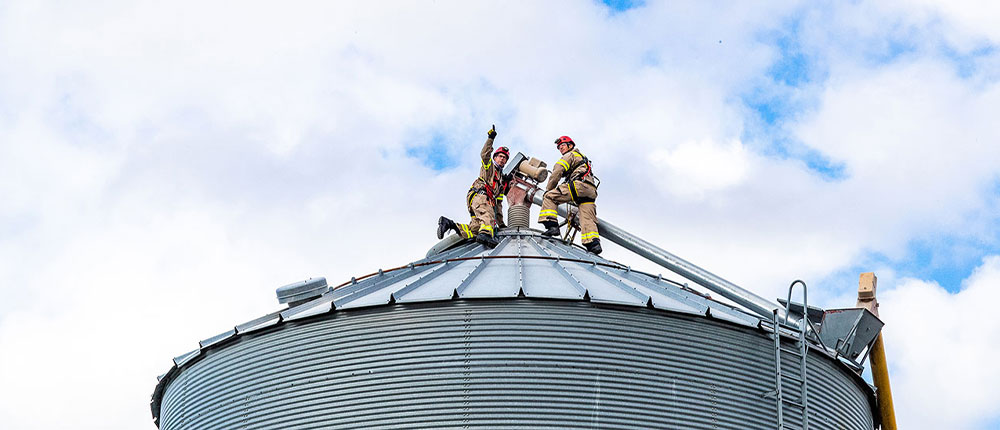Twi firefighters on top of a grain bin