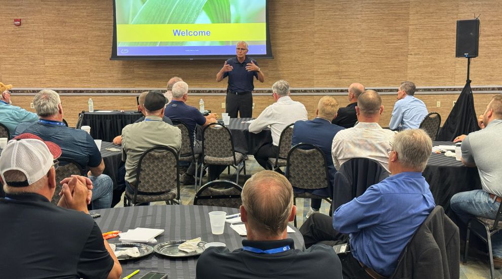 Two men talking at meeting with group of people at a table in background