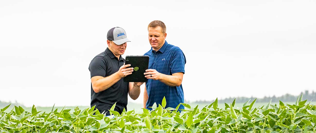 two men in field looking at tablet