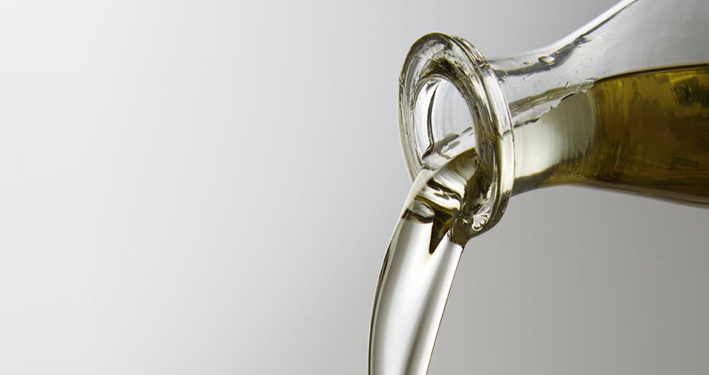 Canola oil pouring from a glass bottle