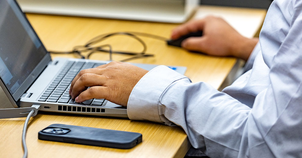 Man's hand typing on a laptop keyboard