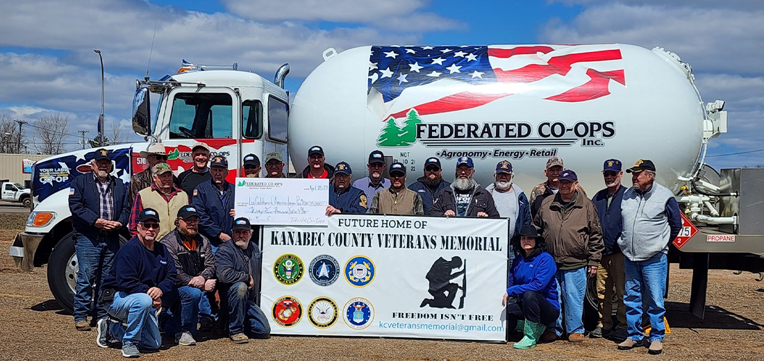 Group of people standing in front of a Federated Co-ops propane tank
