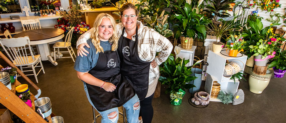 A mother with her arm around her teenage daughter in a flower shop