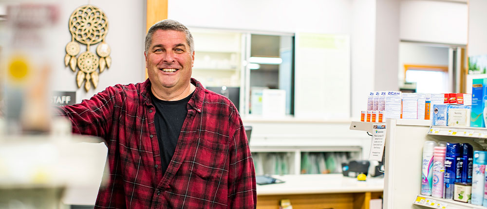 Man standing next to shelves in a pharmacy