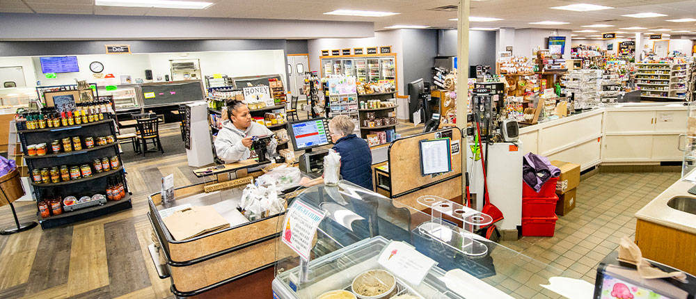Cashier helping a customer inside of a store that sells food, gifts and more