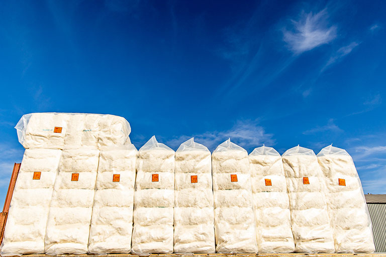 Load of 480-pound bales wrapped in plastic ready for shipment to storage warehouses where it will be sorted by grade and ready for export.