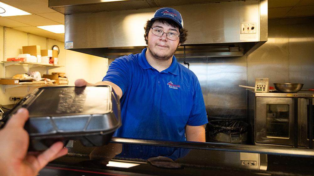 Man hands takeout meal to customer