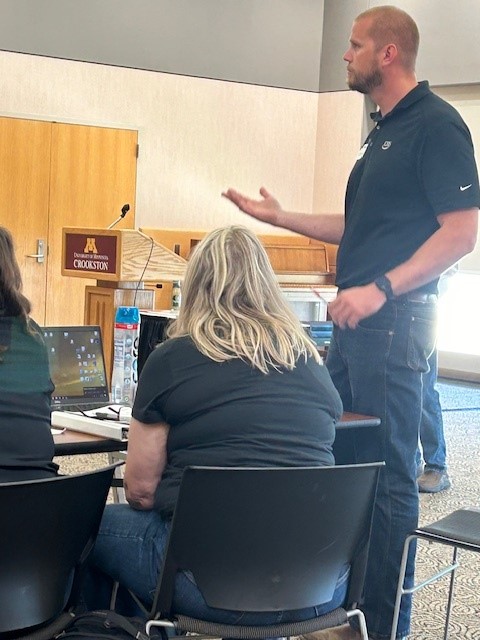 man speaking in front of people seated at tables