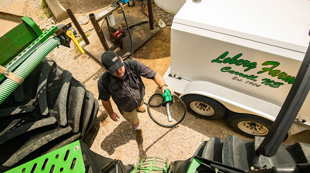 Man holding a fuel hose ready to put diesel fuel in a tractor.