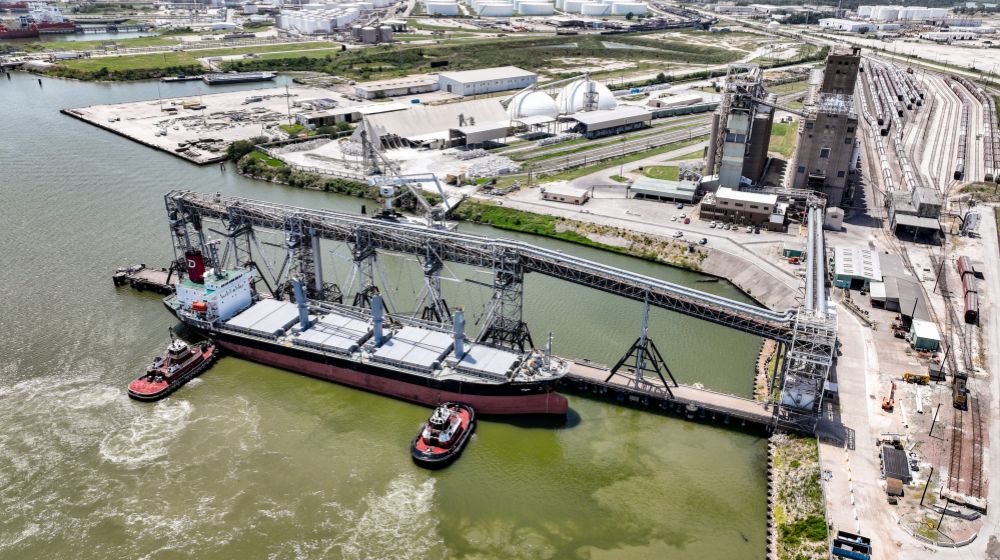 A ship being pushed to a dock by tugboats.  