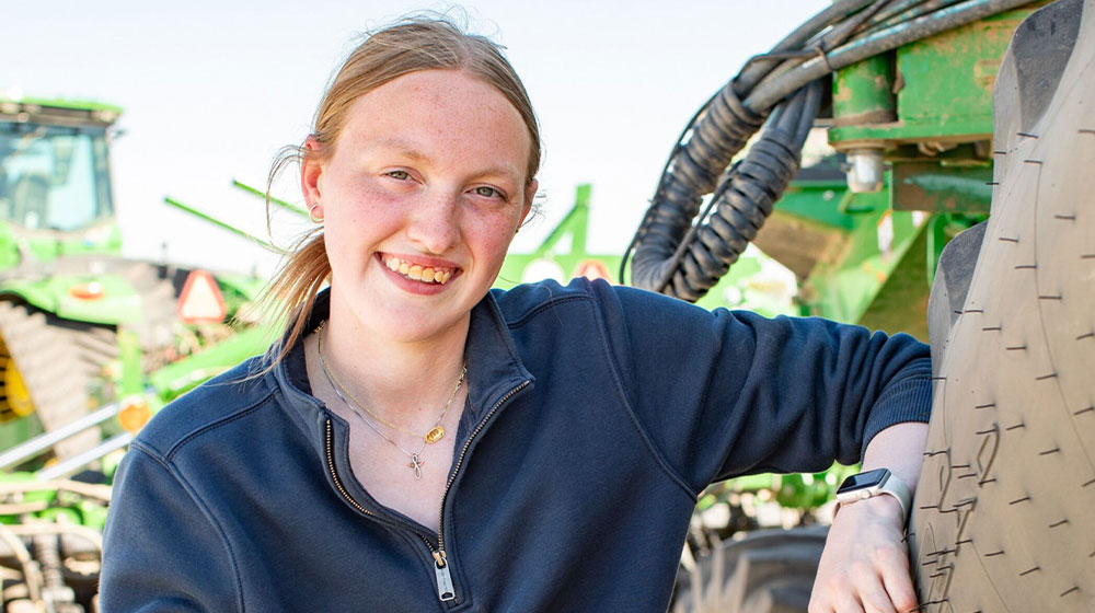 Young woman leaning on tractor tire
