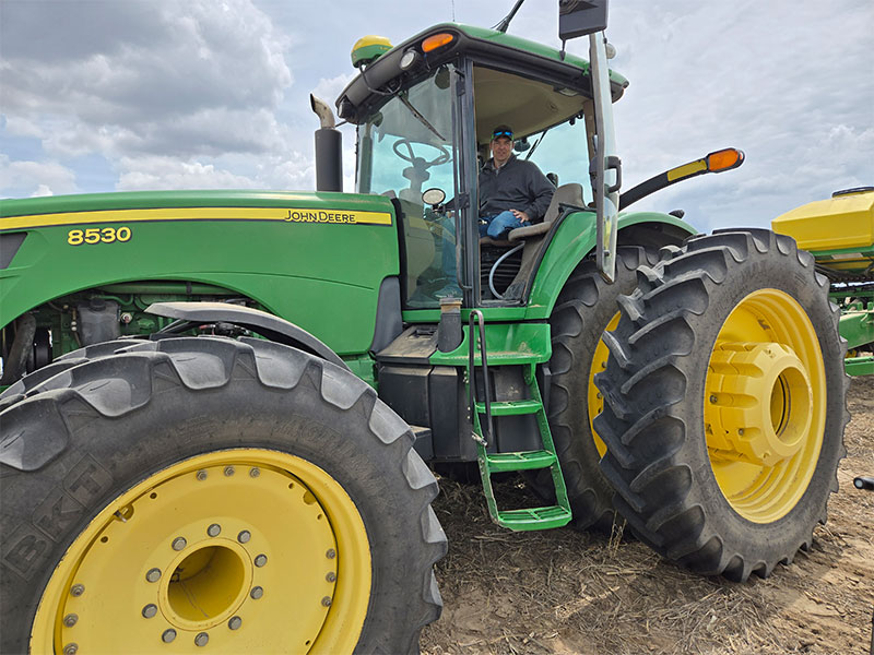 A man who lost his left leg in an accident sits in his John Deere tractor cab